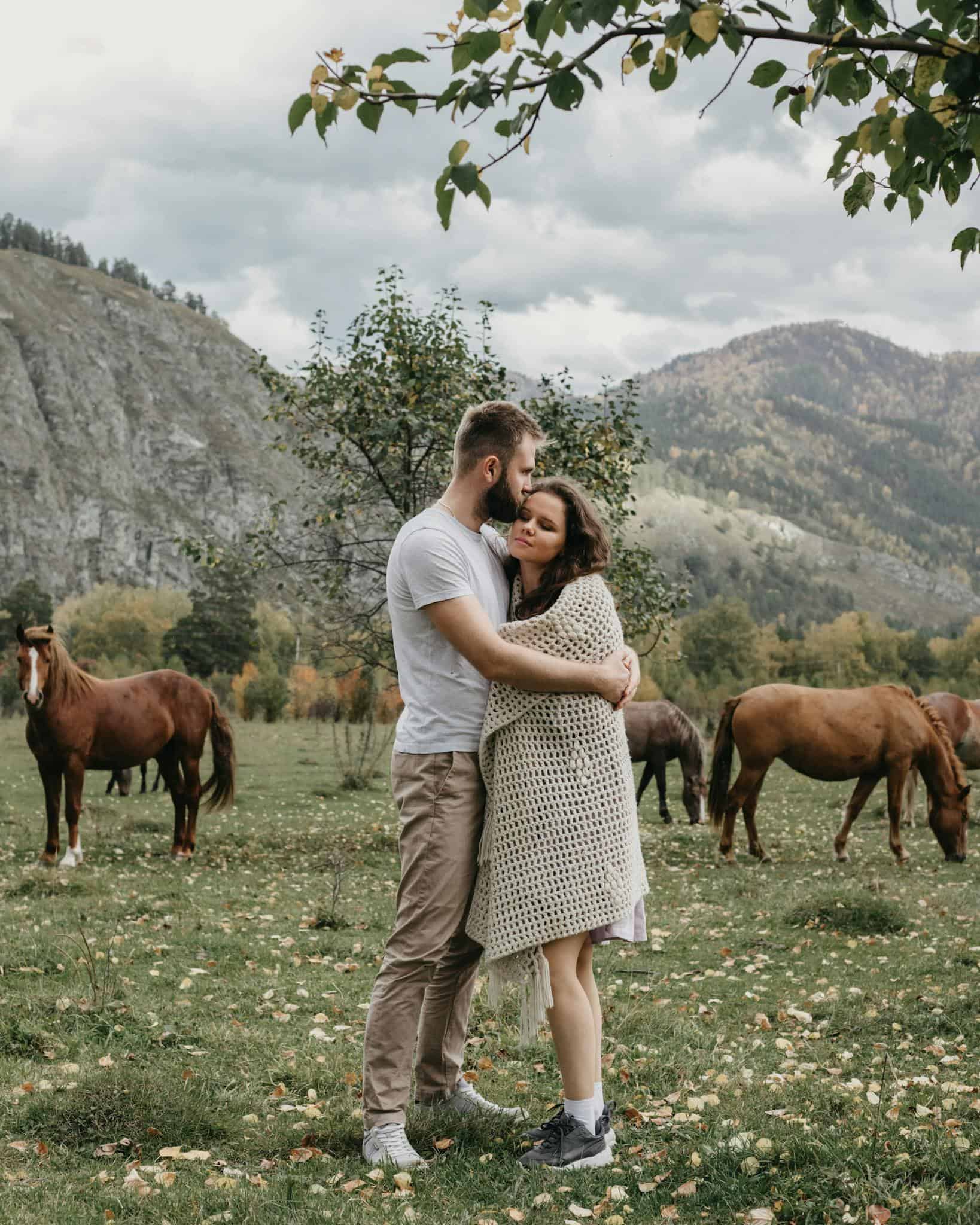 Romantic couple hugging on grassy meadow near mountains